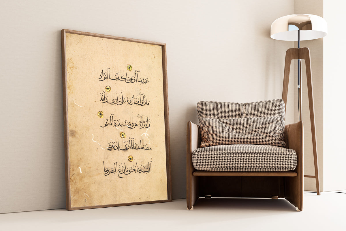 Framed art print of Qur'an Folio: Sura al-Najm (Right Page), leaning against a wall beside an armchair and a floor lamp