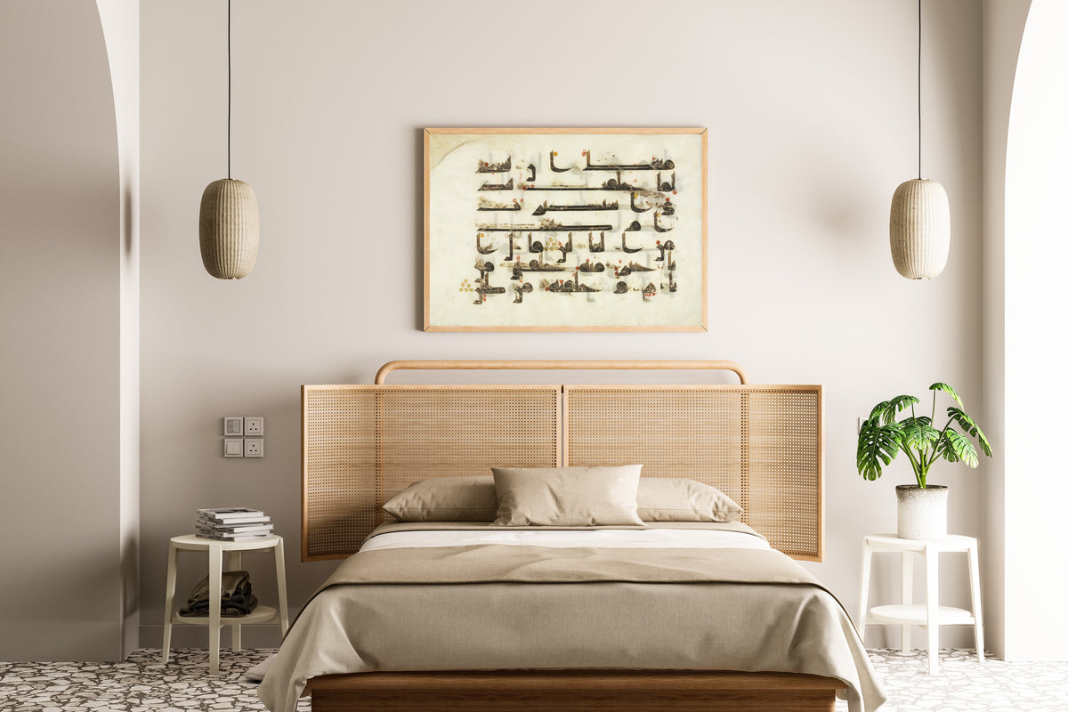 Framed art print of Qur'an Folio: Sura al-Saad, above a cane-headboard bed