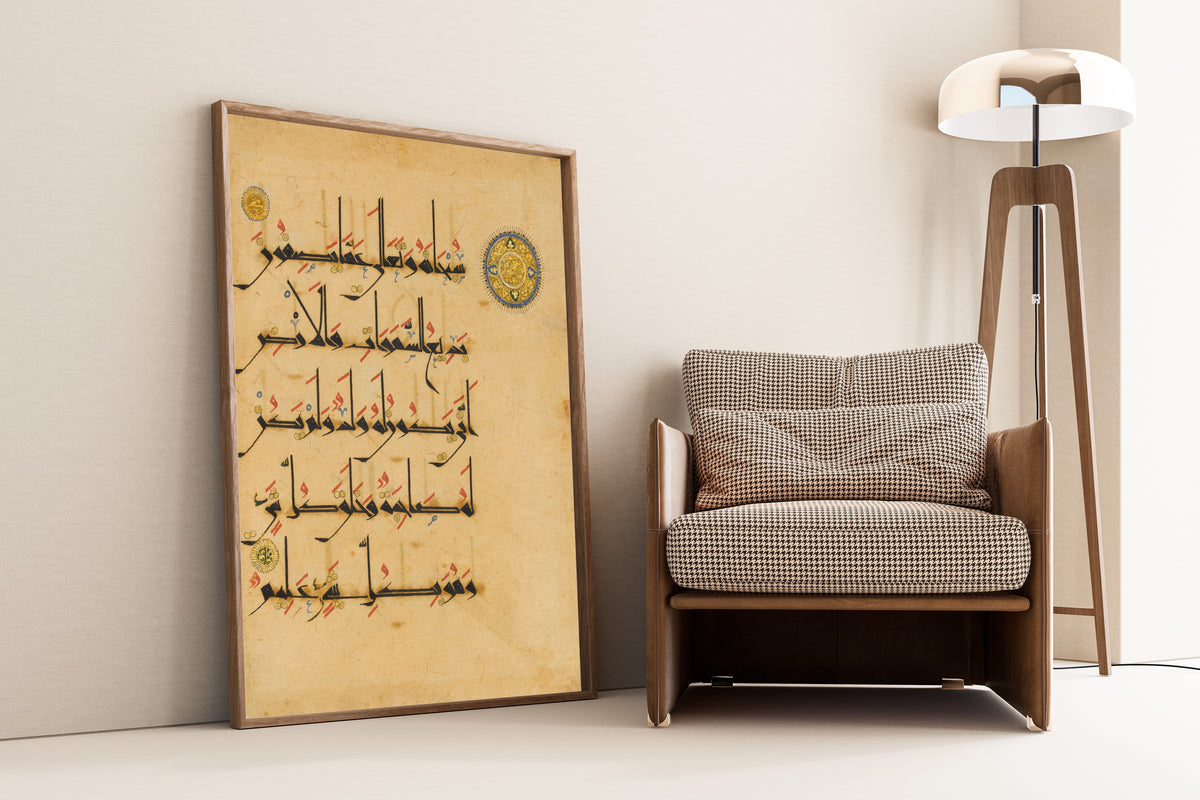 Framed art print of Qur'an Folio (Blue-and-Gold Roundel), leaning against a wall beside an armchair and a floor lamp