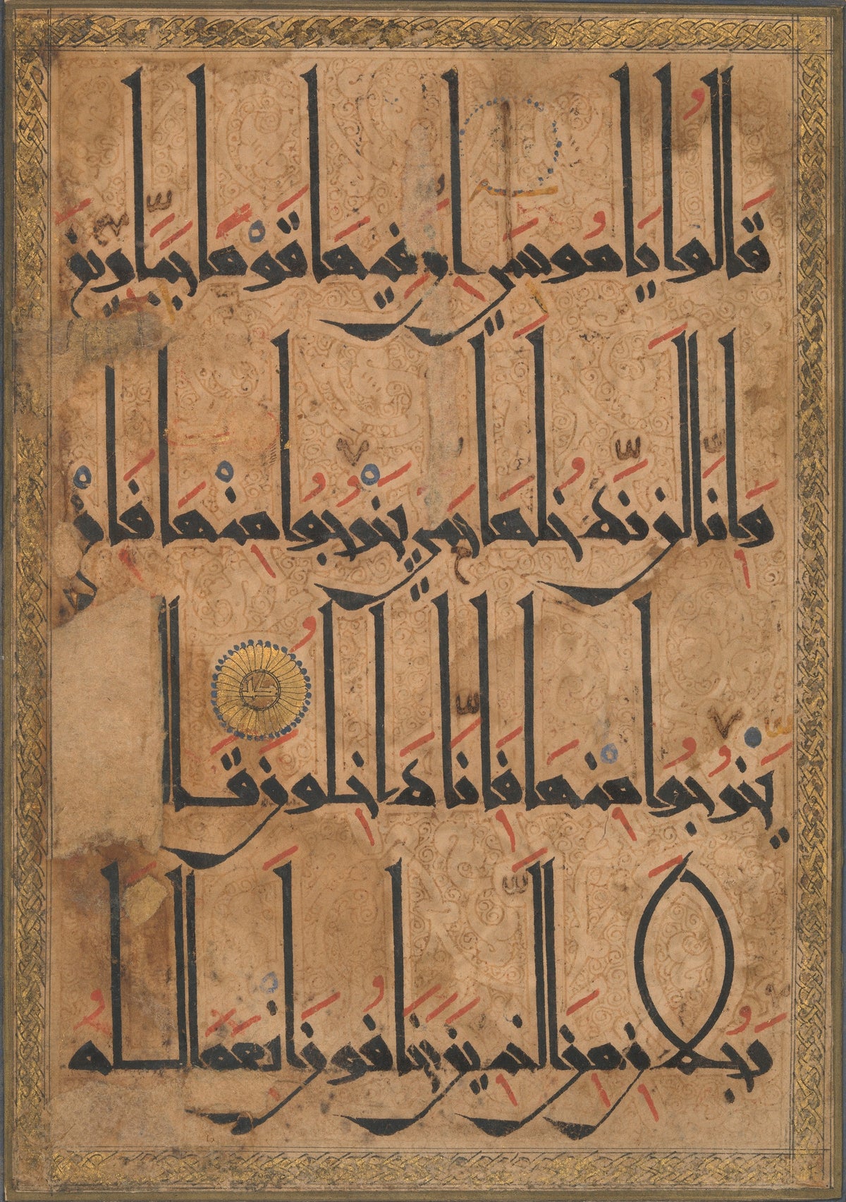 Qur'an Folio (Gold Roundel on Arabesque Ground) — Tall black letters over a ground of brown scrolling arabesques