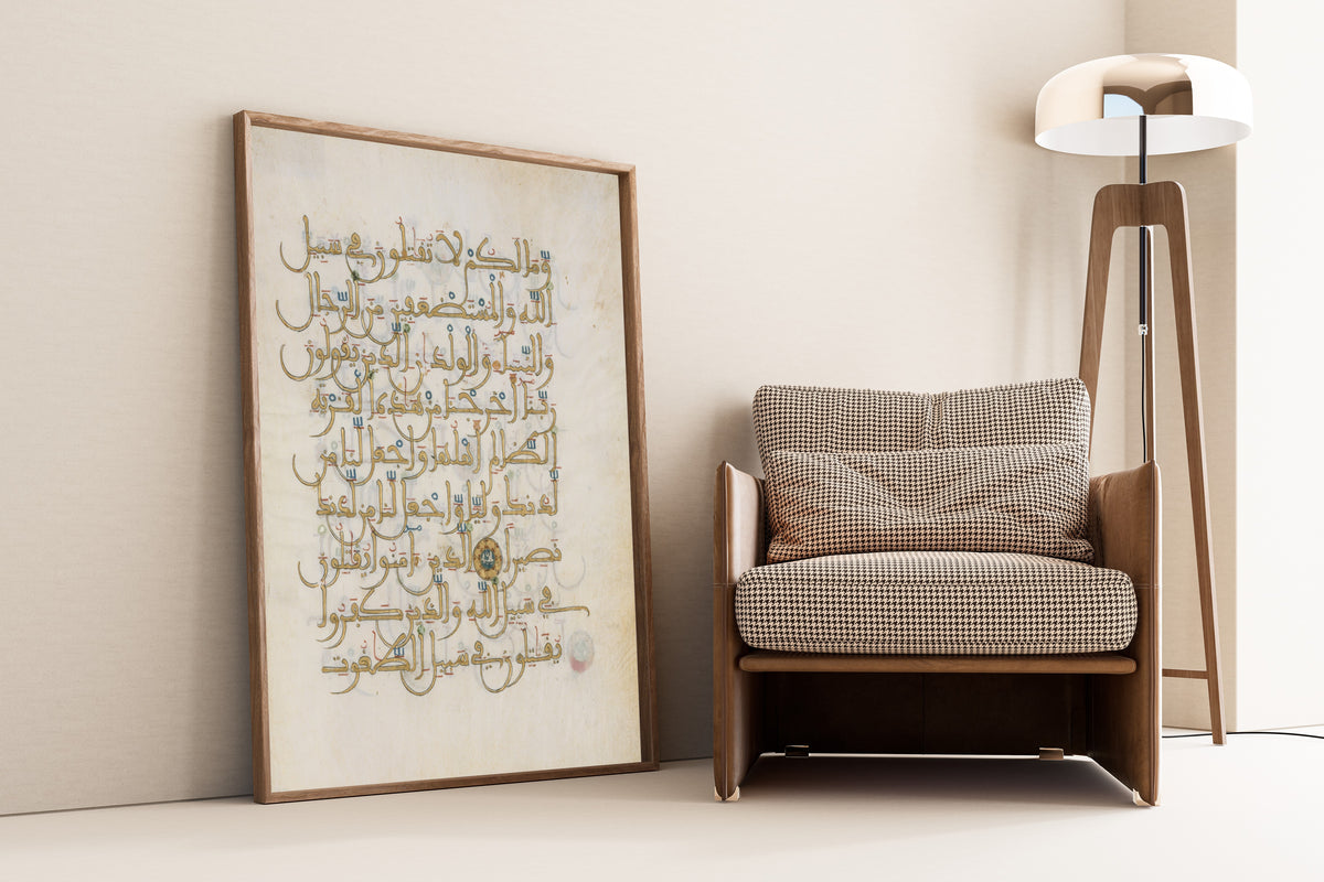 Framed art print of Qur'an Folio (Gold Script with Blue Roundel), leaning against a wall beside an armchair and a floor lamp