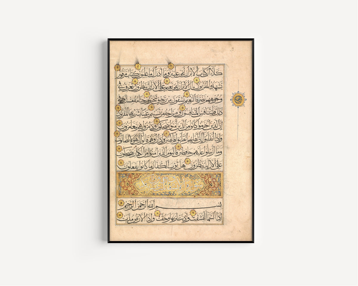 Framed art print of Qur'an Folio (Illuminated Sura Heading), in a slim black frame on a plain white wall