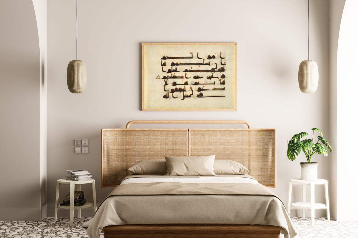 Framed art print of Qur'an Folio (Red and Green Dots on Parchment), above a cane-headboard bed