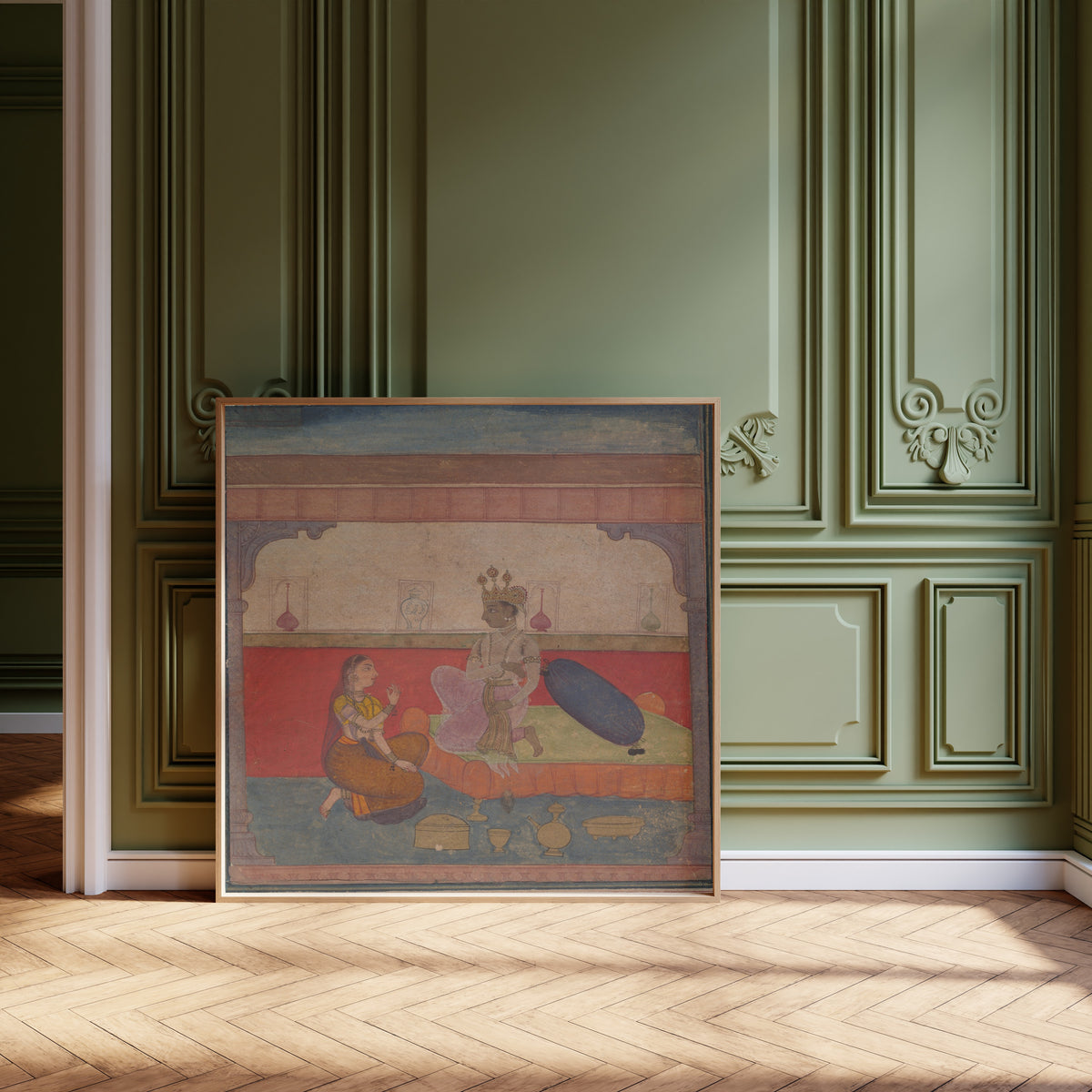 Framed art print of Radha Speaks to Krishna by Amber school, leaning against olive-green panelling on a herringbone floor