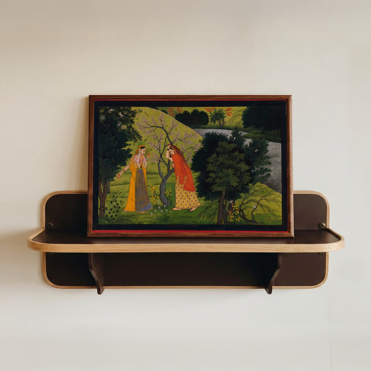 Framed art print of Radha with Her Confidant, Pining for Krishna by Garhwal school, in a dark wood frame resting on a wall shelf