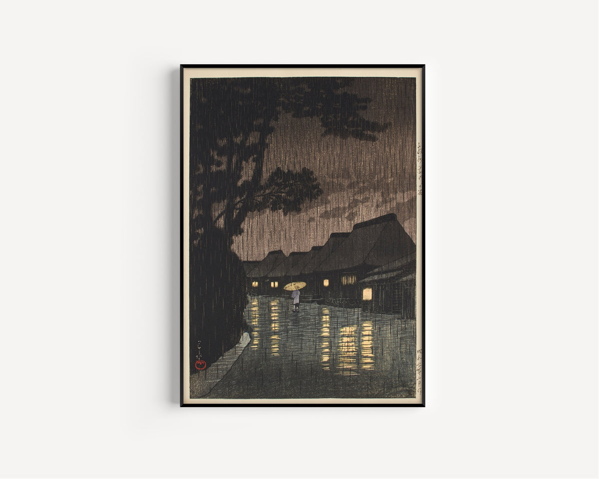 Framed art print of Rain at Maekawa, Sagami Province by Kawase Hasui, in a slim black frame on a plain white wall