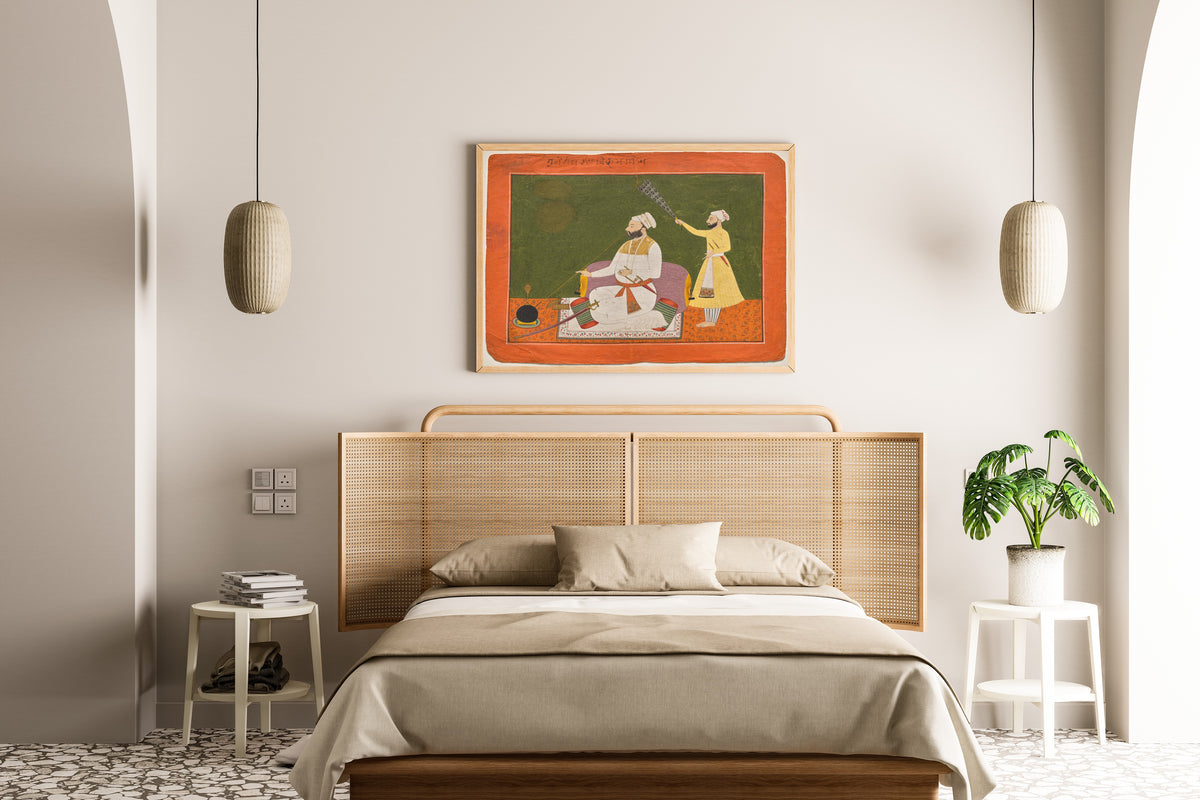 Framed art print of Raja Bikram Singh of Guler Smoking a Hookah by Pahari school, above a cane-headboard bed
