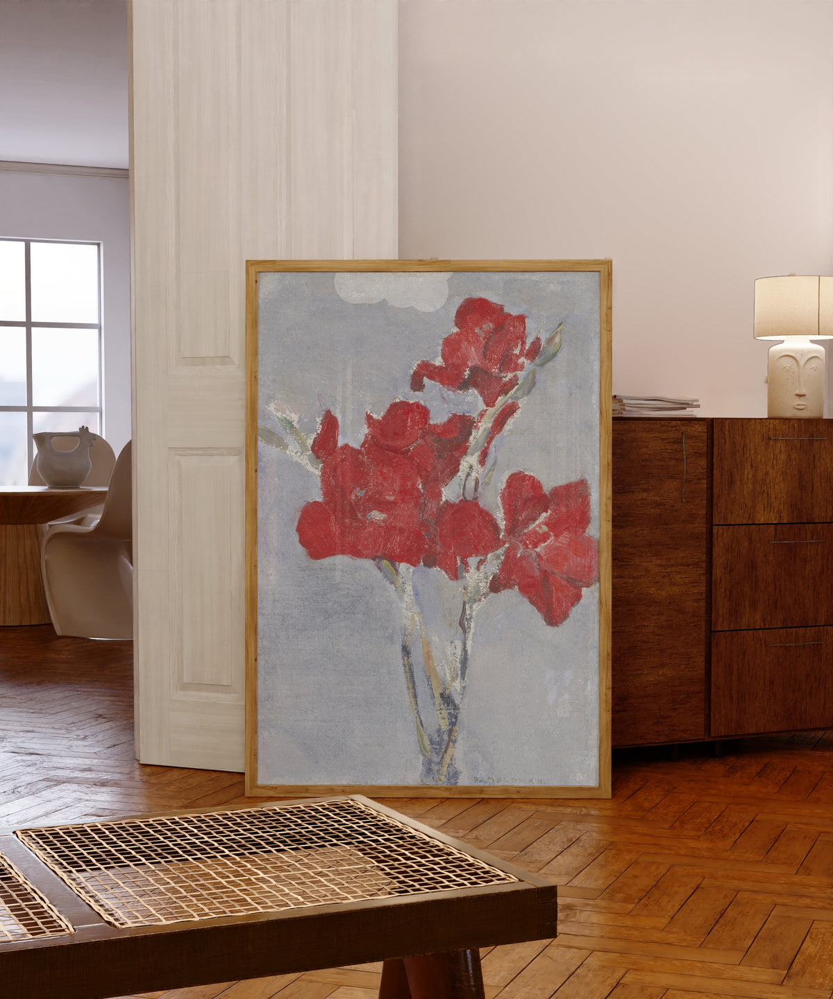 Framed art print of Red Gladioli by Piet Mondrian, in a light wood frame leaning in a warm room with a parquet floor