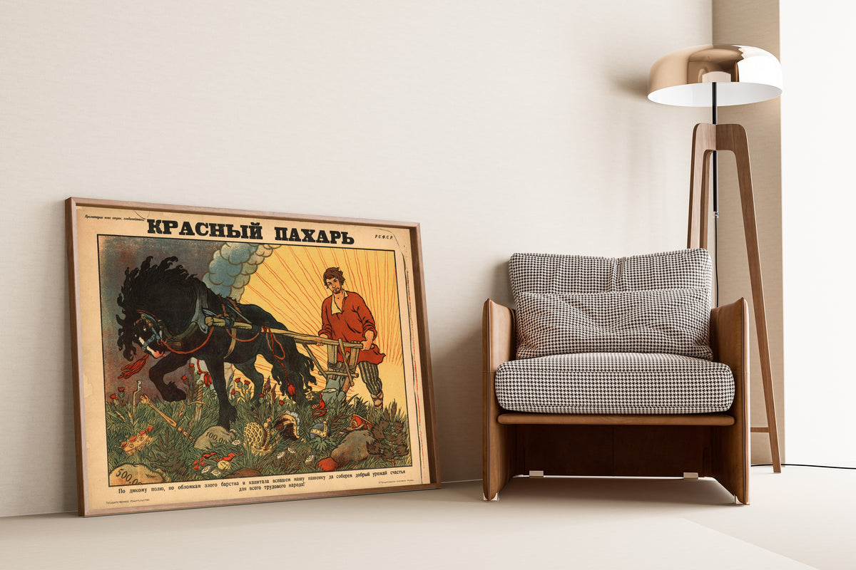 Framed art print of Red Ploughman by Boris Zvorykin, leaning against a wall beside an armchair and a floor lamp