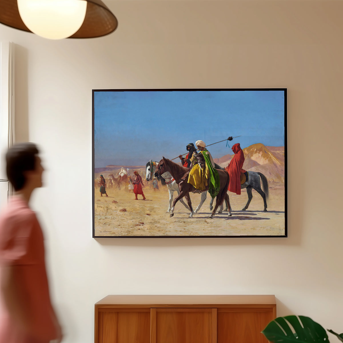 Framed art print of Riders Crossing the Desert by Jean-Léon Gérôme, in a slim black frame on a warm wall in a sunlit room