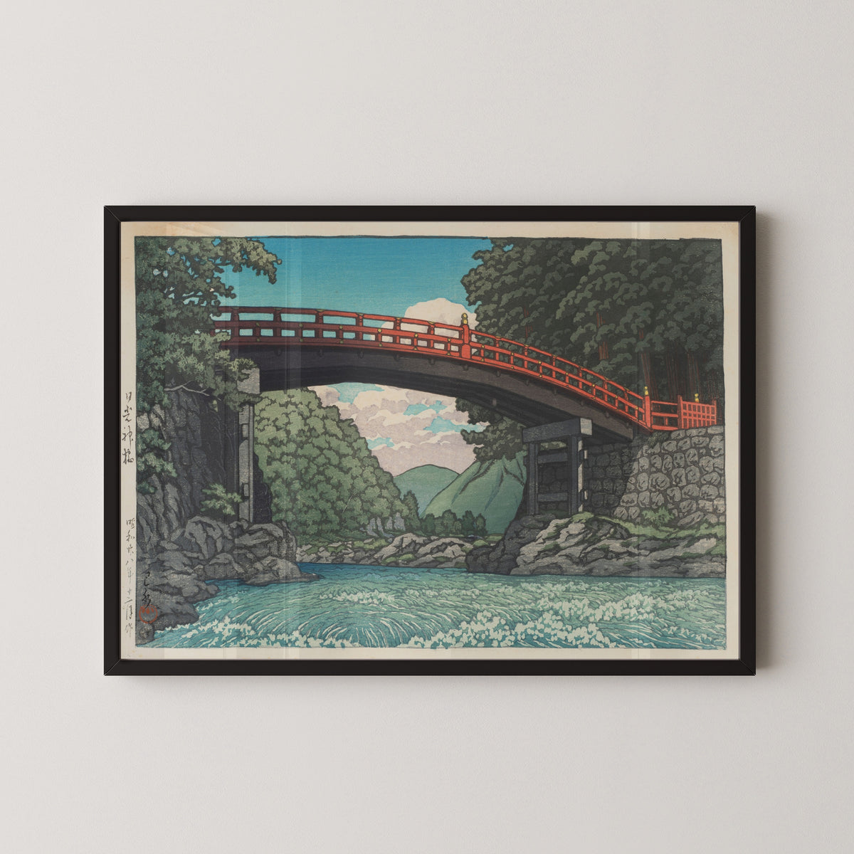 Framed art print of Sacred Bridge, Nikko by Kawase Hasui, in a black frame on a pale wall