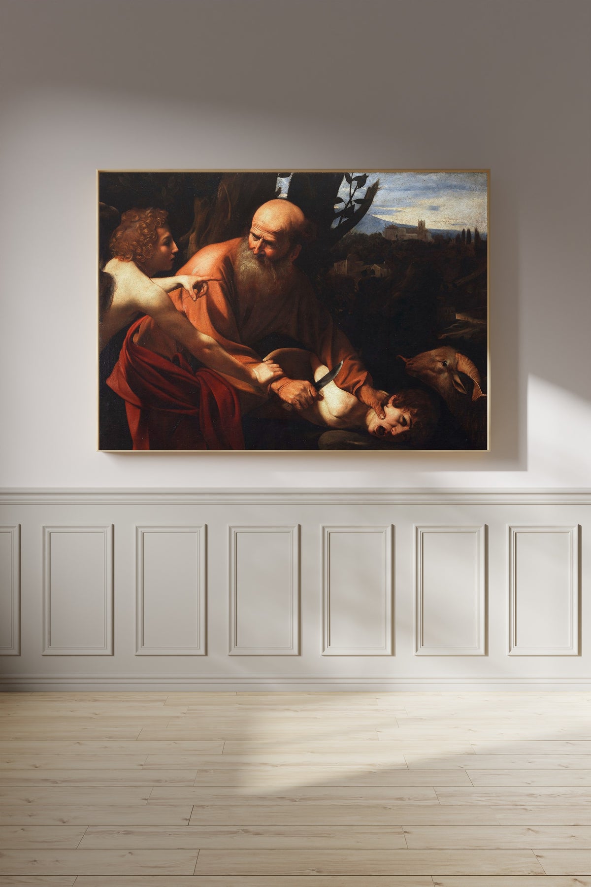 Framed art print of Sacrifice of Isaac by Caravaggio, on a panelled wall in afternoon light