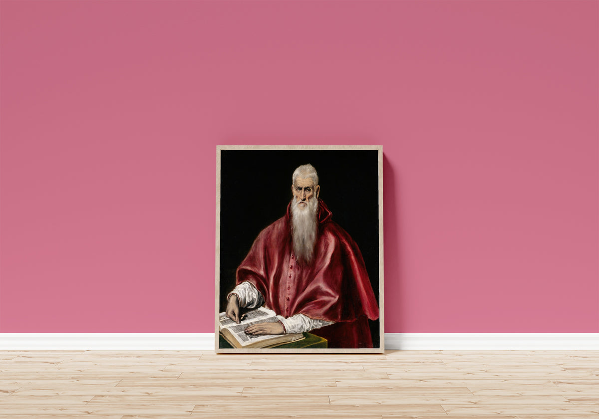 Framed art print of Saint Jerome as Scholar by El Greco, in a light wood frame leaning on a pink wall above a wooden floor