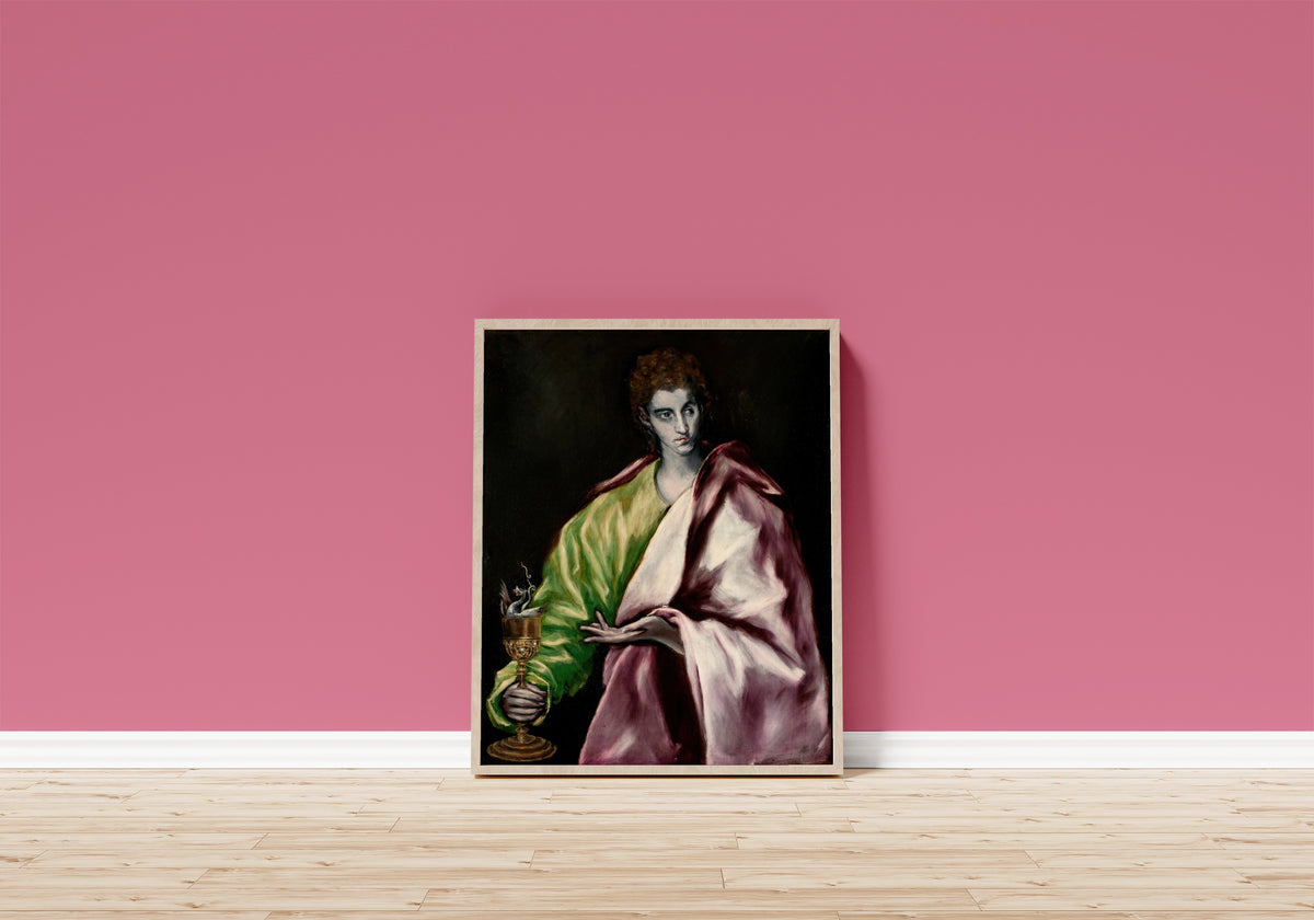 Framed art print of Saint John the Evangelist by El Greco, in a light wood frame leaning on a pink wall above a wooden floor