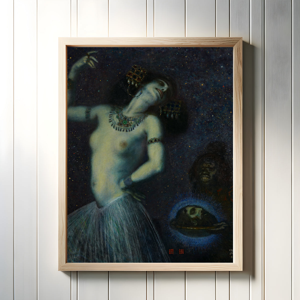Framed art print of Salome by Franz von Stuck, in a light wood frame on a white panelled wall