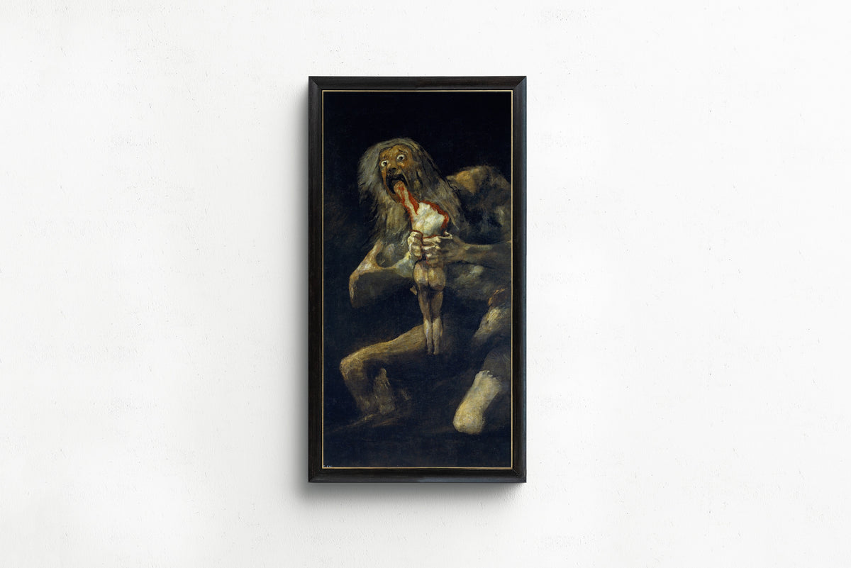 Framed art print of Saturn Devouring His Son by Francisco de Goya, in a slim black frame on a plain white wall