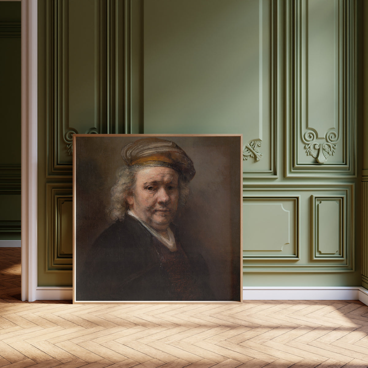 Framed art print of Self-Portrait (1669) by Rembrandt van Rijn, leaning against olive-green panelling on a herringbone floor