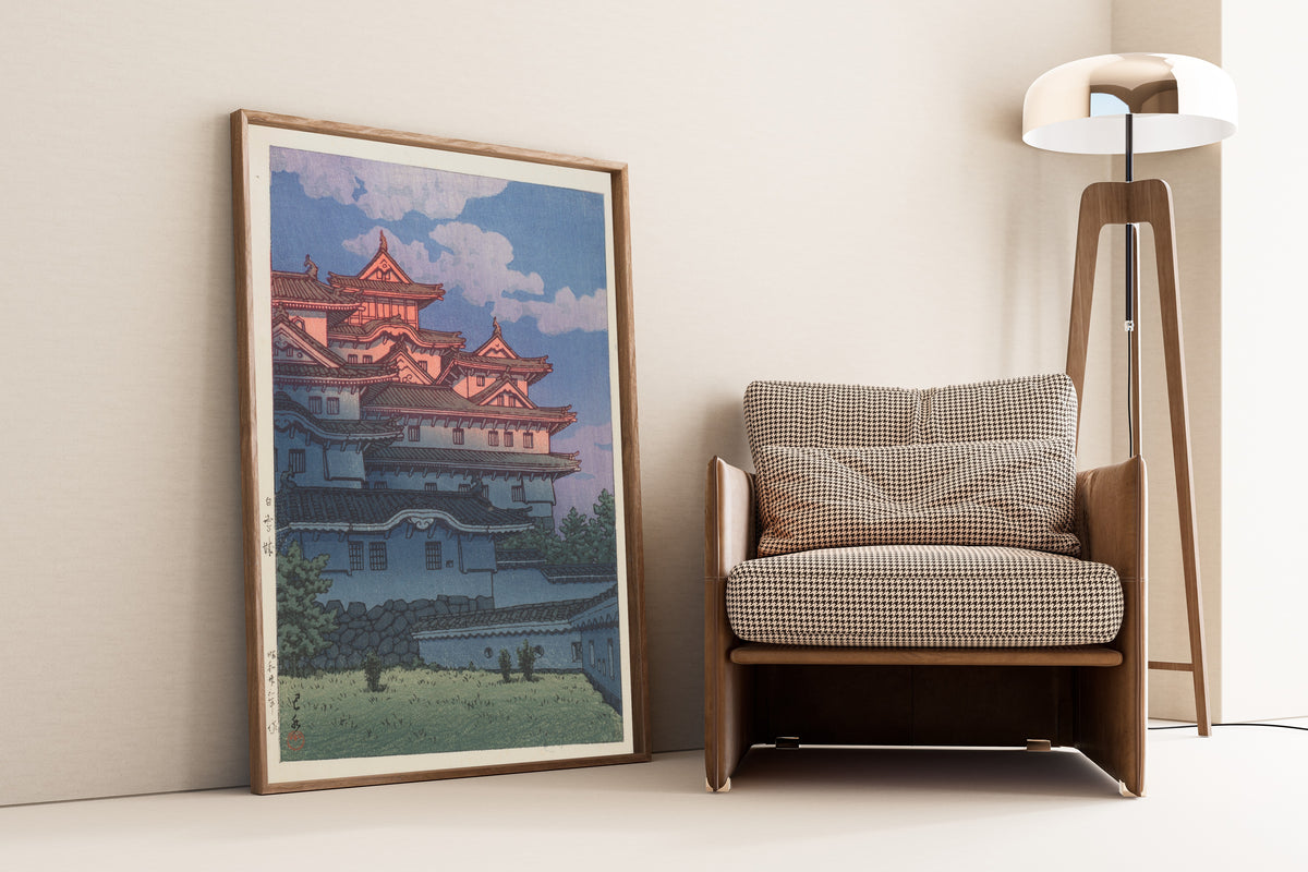 Framed art print of Shirasagi Castle by Kawase Hasui, leaning against a wall beside an armchair and a floor lamp