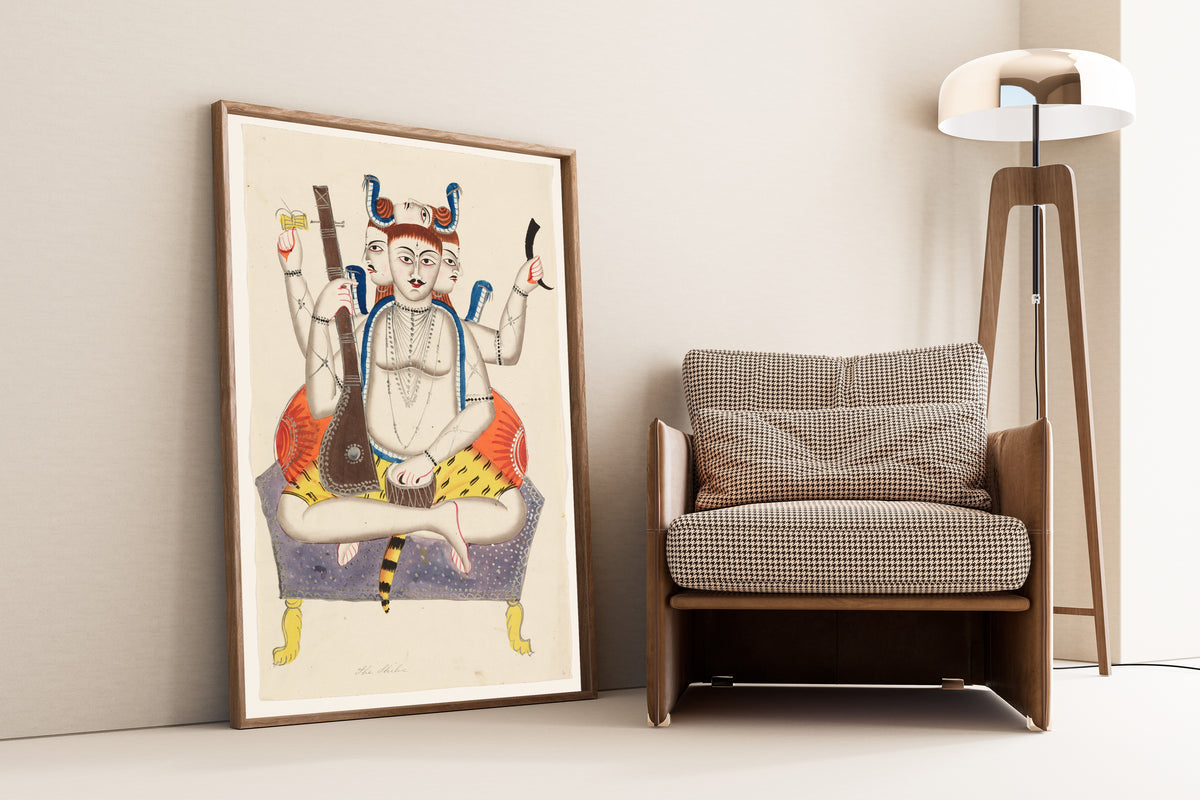 Framed art print of Shiva by Kalighat painter, leaning against a wall beside an armchair and a floor lamp
