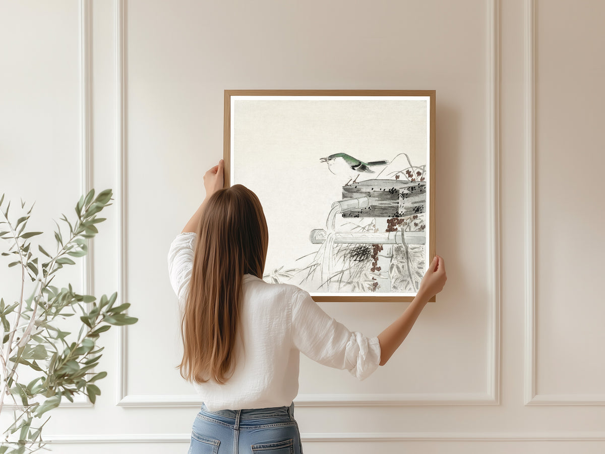Framed art print of Siberian Blue Robin at a Bamboo Water Spout by Ohara Koson, hung on a panelled wall