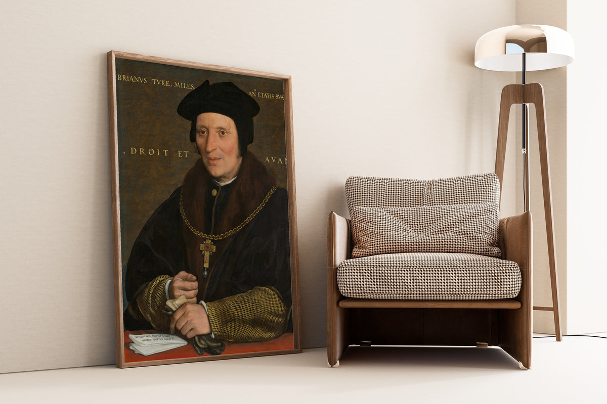 Framed art print of Sir Brian Tuke by Hans Holbein the Younger, leaning against a wall beside an armchair and a floor lamp