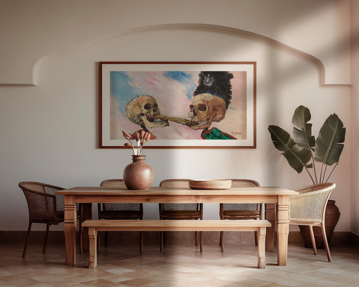 Framed art print of Skeletons Fighting over a Pickled Herring by James Ensor, above a wooden dining table