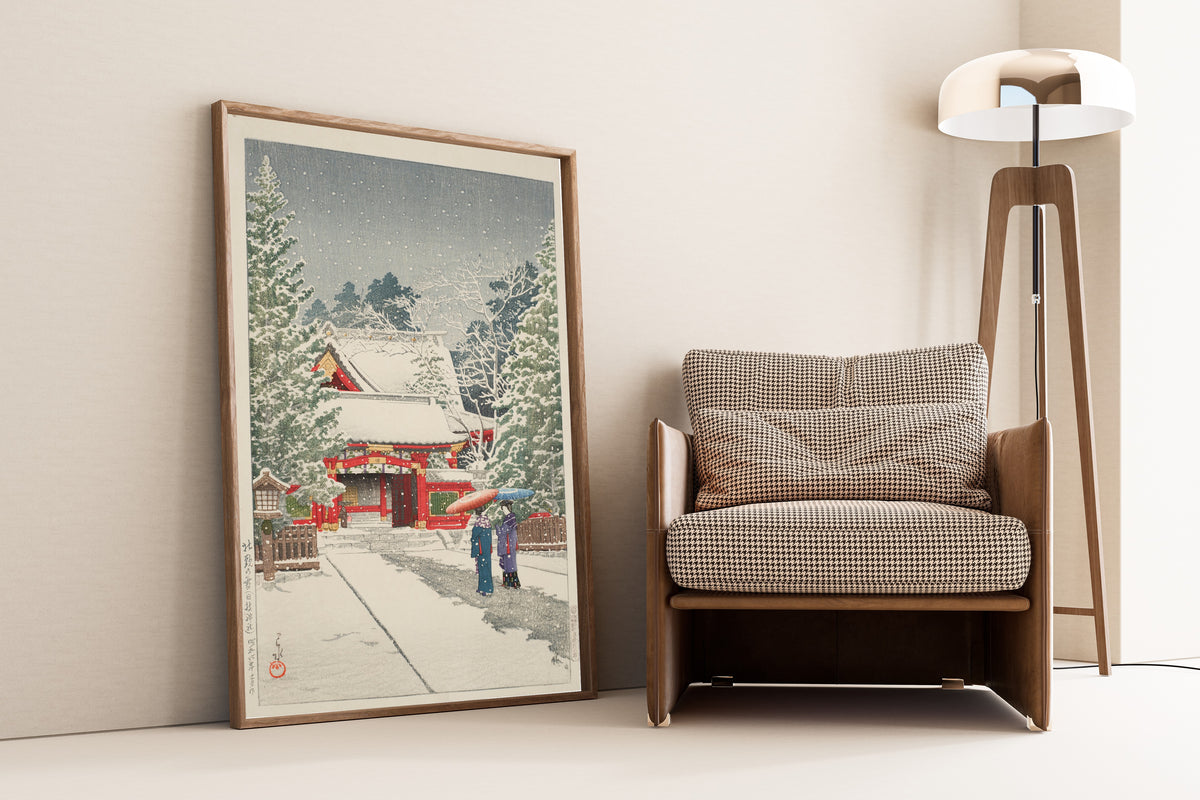 Framed art print of Snow at Hie Shrine by Kawase Hasui, leaning against a wall beside an armchair and a floor lamp