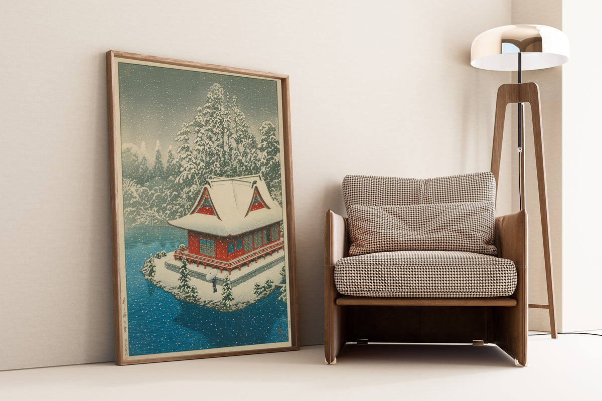 Framed art print of Snow at Inokashira by Kawase Hasui, leaning against a wall beside an armchair and a floor lamp