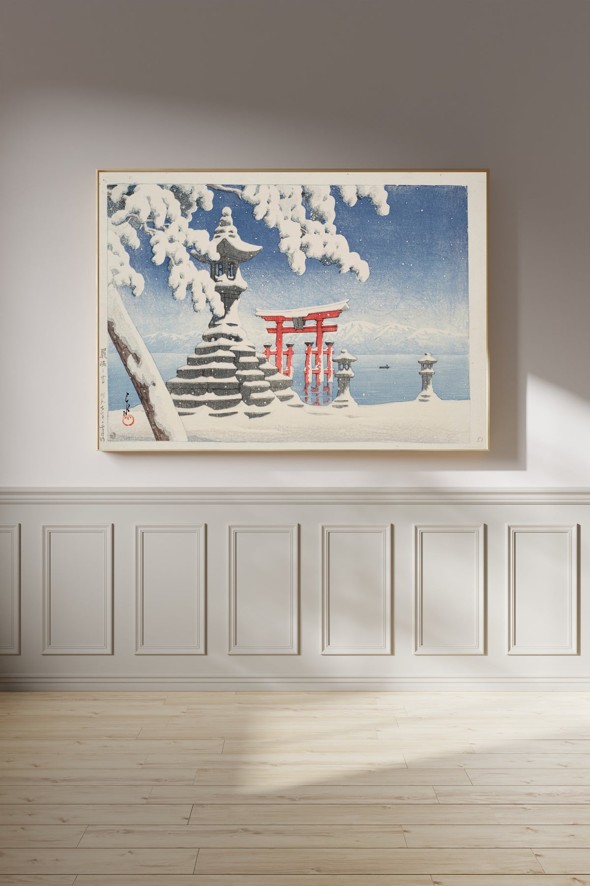Framed art print of Snow at Itsukushima by Kawase Hasui, on a panelled wall in afternoon light