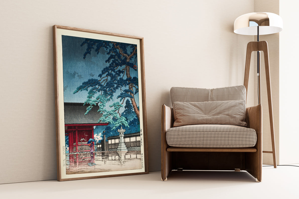 Framed art print of Spring Rain at Gokokuji Temple by Kawase Hasui, leaning against a wall beside an armchair and a floor lamp