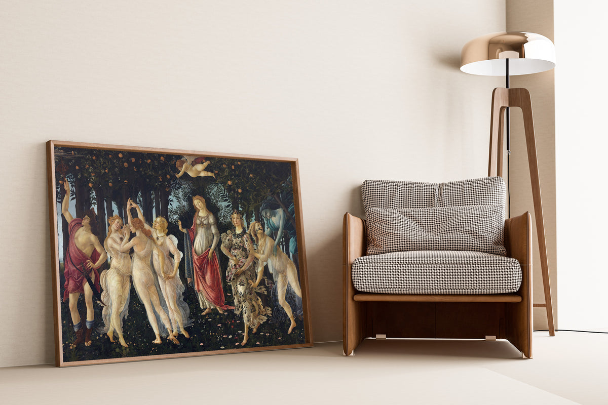 Framed art print of Spring by Sandro Botticelli, leaning against a wall beside an armchair and a floor lamp