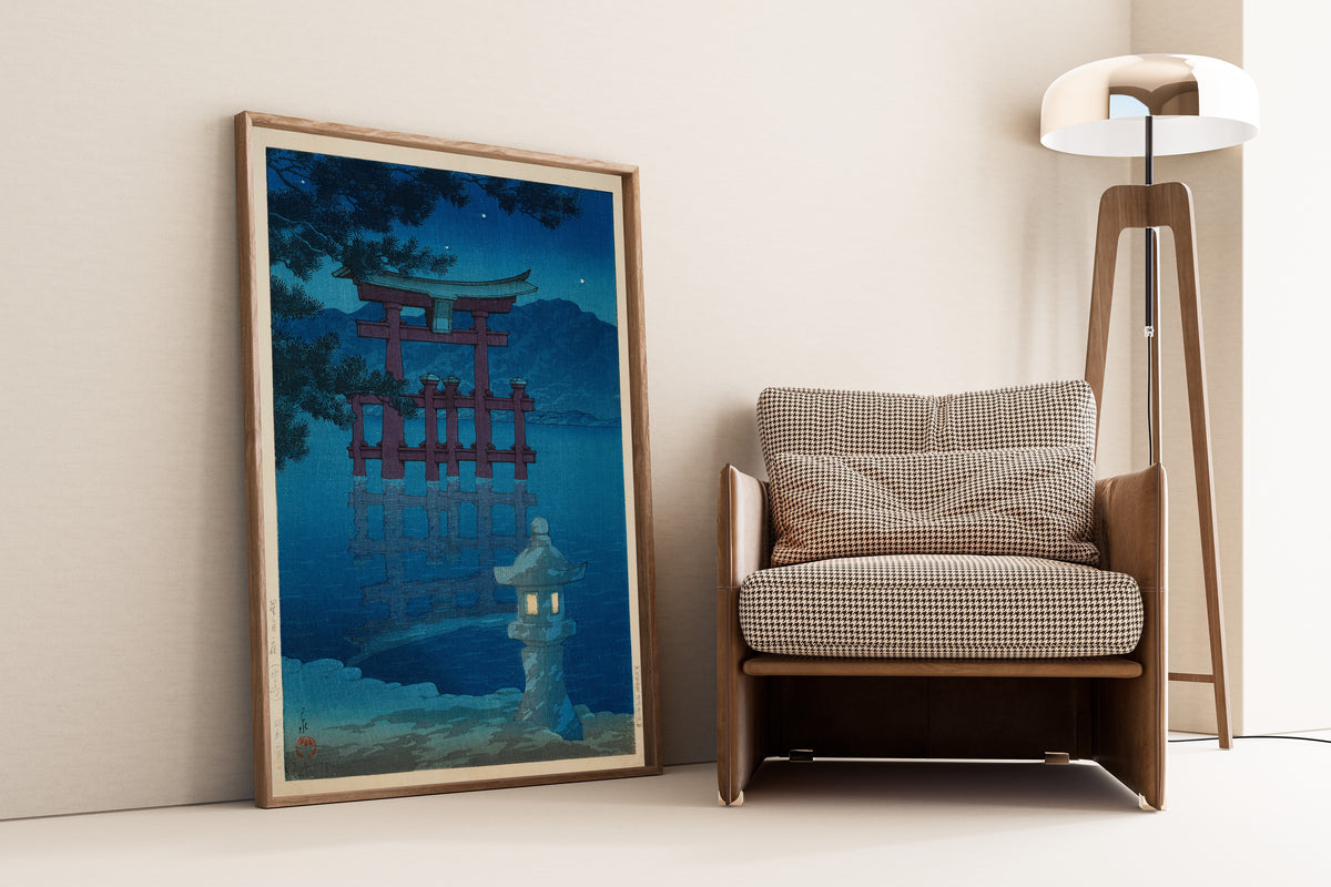 Framed art print of Starlit Night at Miyajima by Kawase Hasui, leaning against a wall beside an armchair and a floor lamp