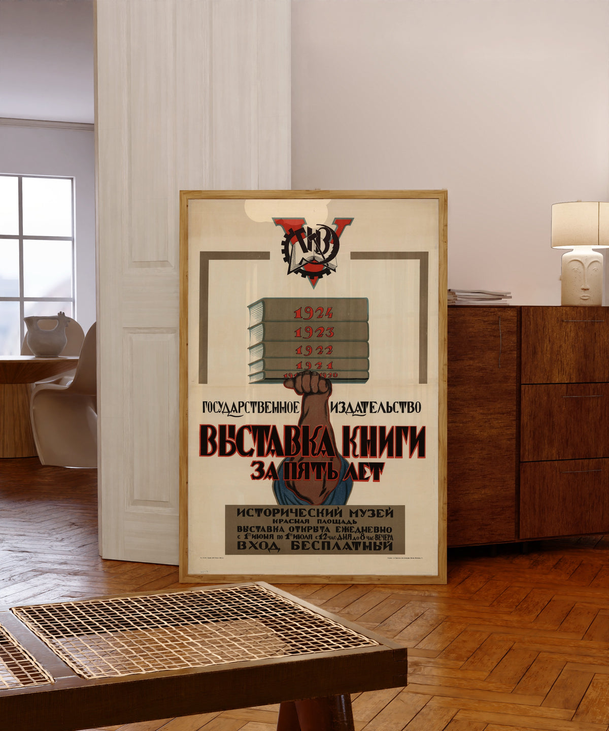 Framed art print of State Publishing House: five years of the book exhibition, in a light wood frame leaning in a warm room with a parquet floor
