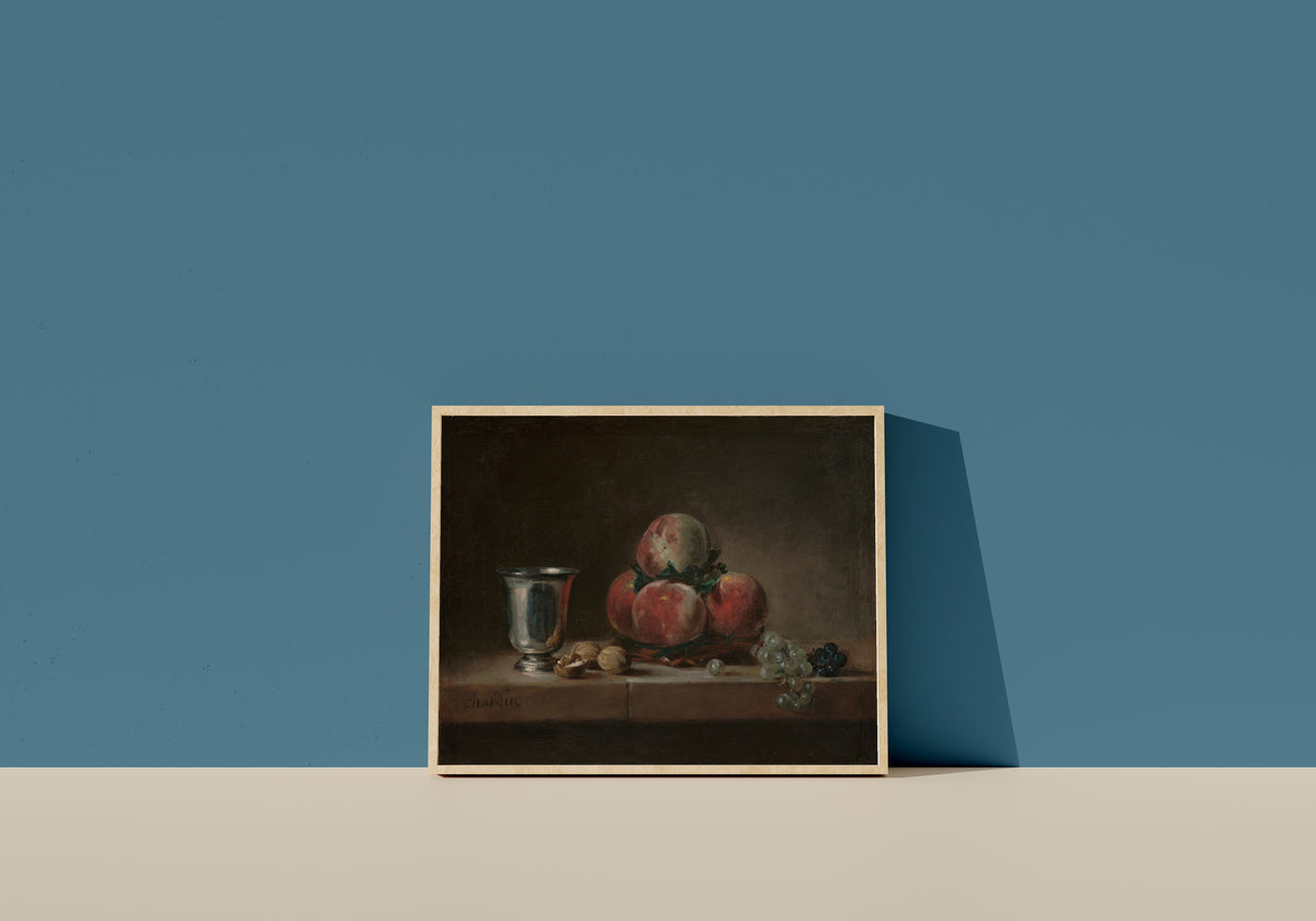Framed art print of Still Life with Peaches, a Silver Goblet, Grapes, and Walnuts by Jean-Siméon Chardin, in a light wood frame leaning on a blue wall