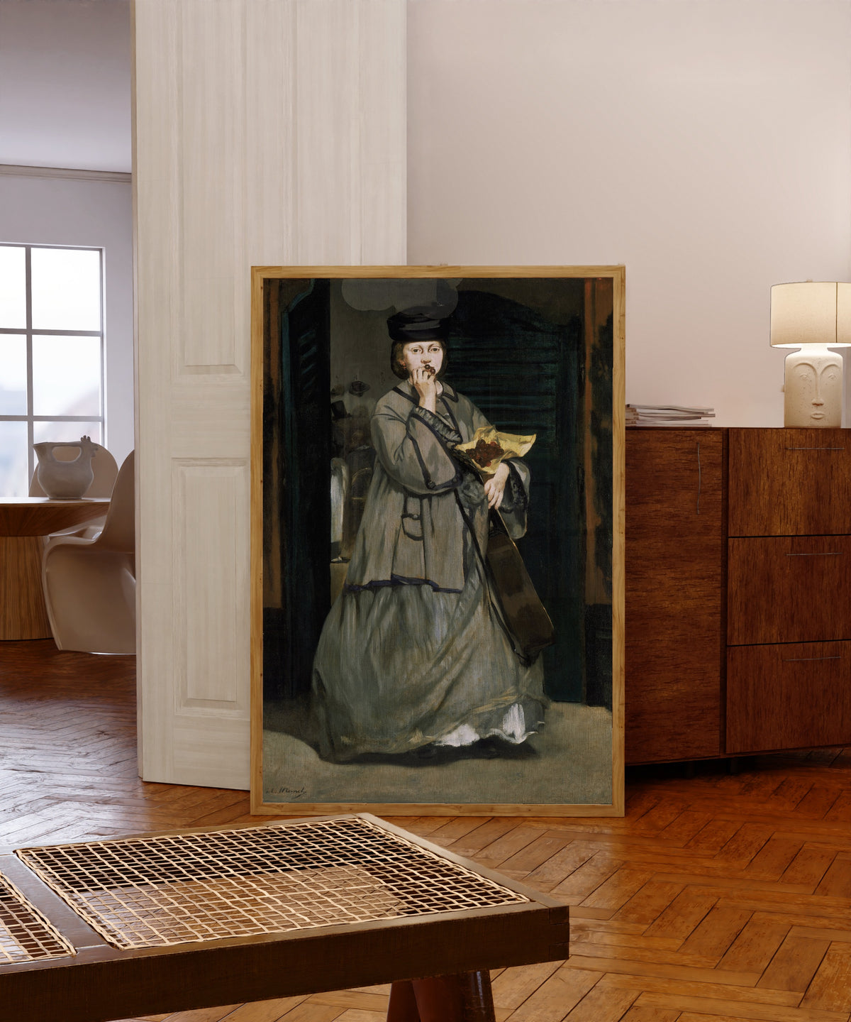 Framed art print of Street Singer by Édouard Manet, in a light wood frame leaning in a warm room with a parquet floor