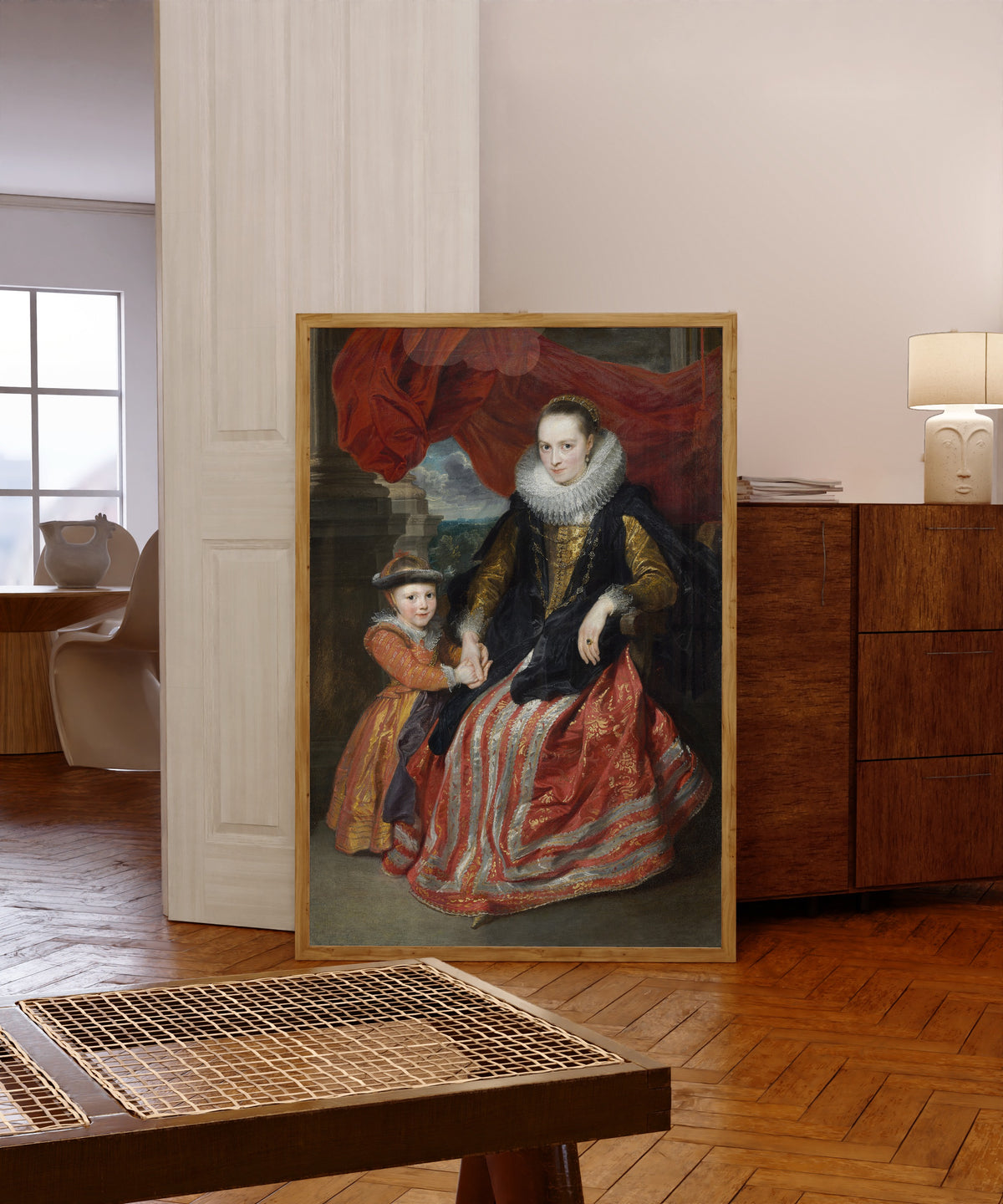 Framed art print of Susanna Fourment and Her Daughter by Anthony van Dyck, in a light wood frame leaning in a warm room with a parquet floor