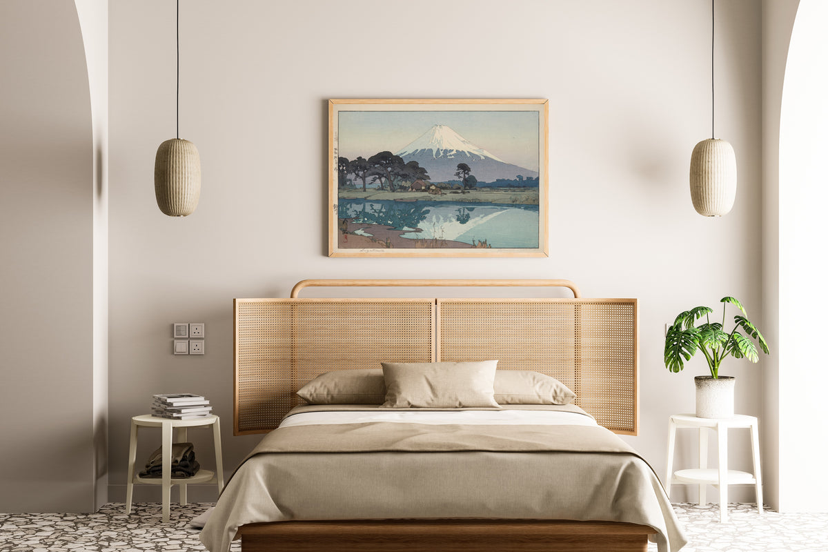 Framed art print of Suzukawa by Hiroshi Yoshida, above a cane-headboard bed