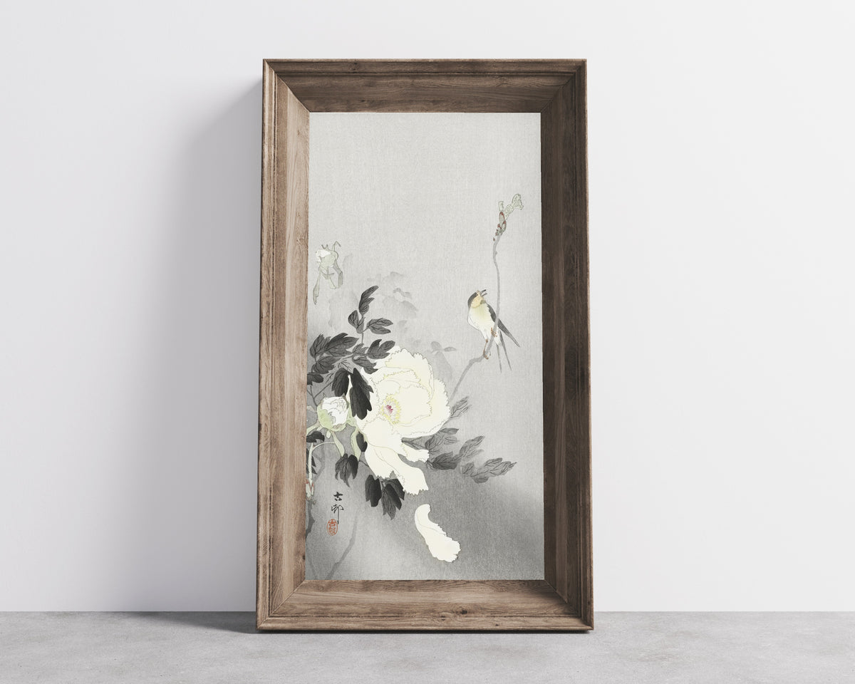 Framed art print of Swallow with Peony by Ohara Koson, in a wide wooden frame leaning against a concrete wall