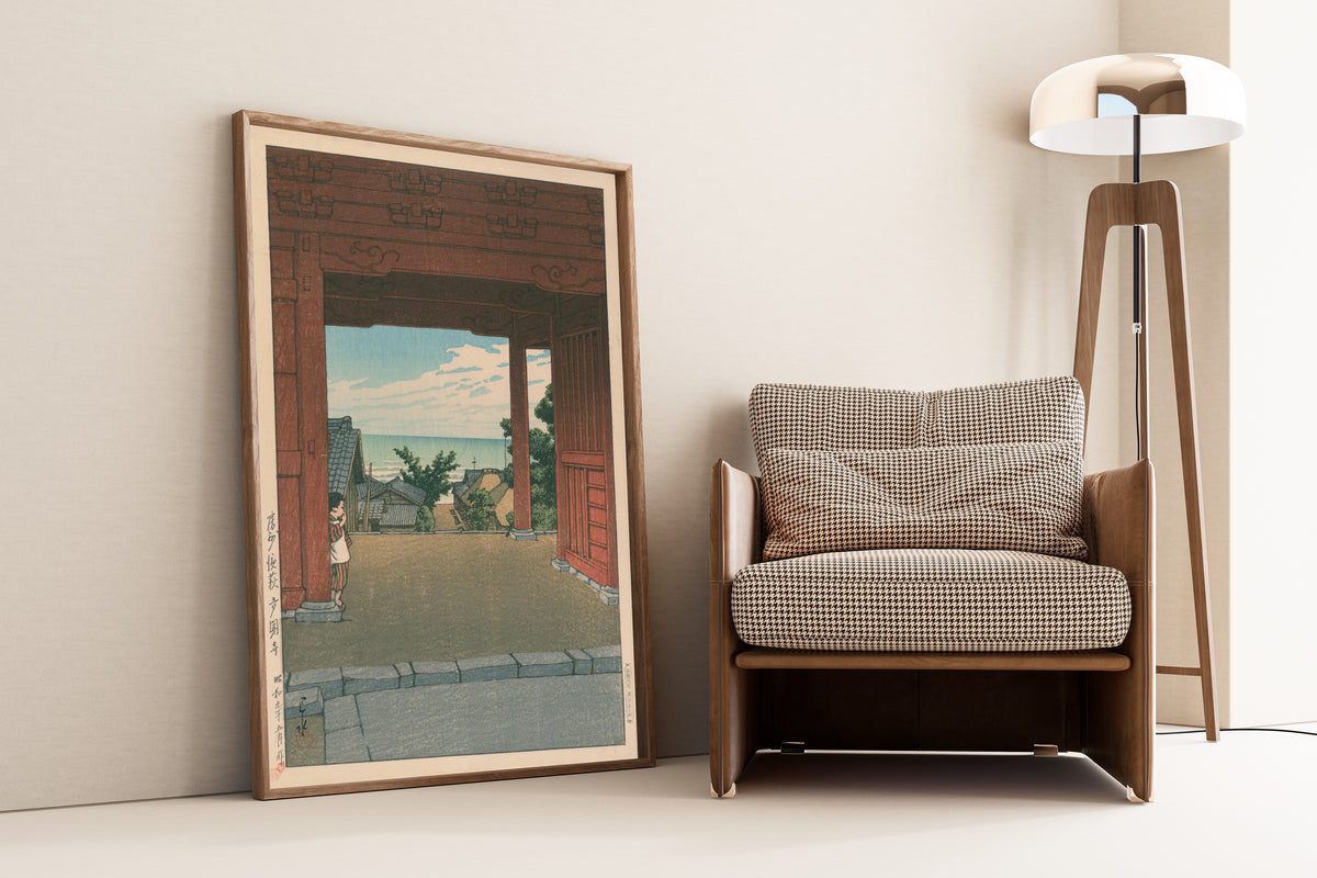 Framed art print of Tamon Temple at Hamahagi, Awa Province by Kawase Hasui, leaning against a wall beside an armchair and a floor lamp
