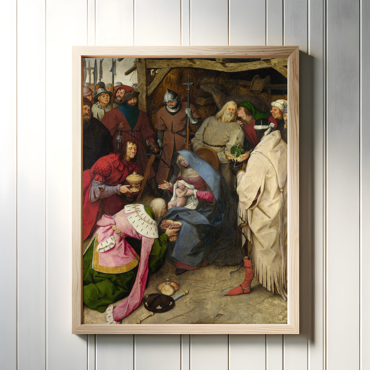 Framed art print of The Adoration of the Kings by Pieter Bruegel the Elder, in a light wood frame on a white panelled wall