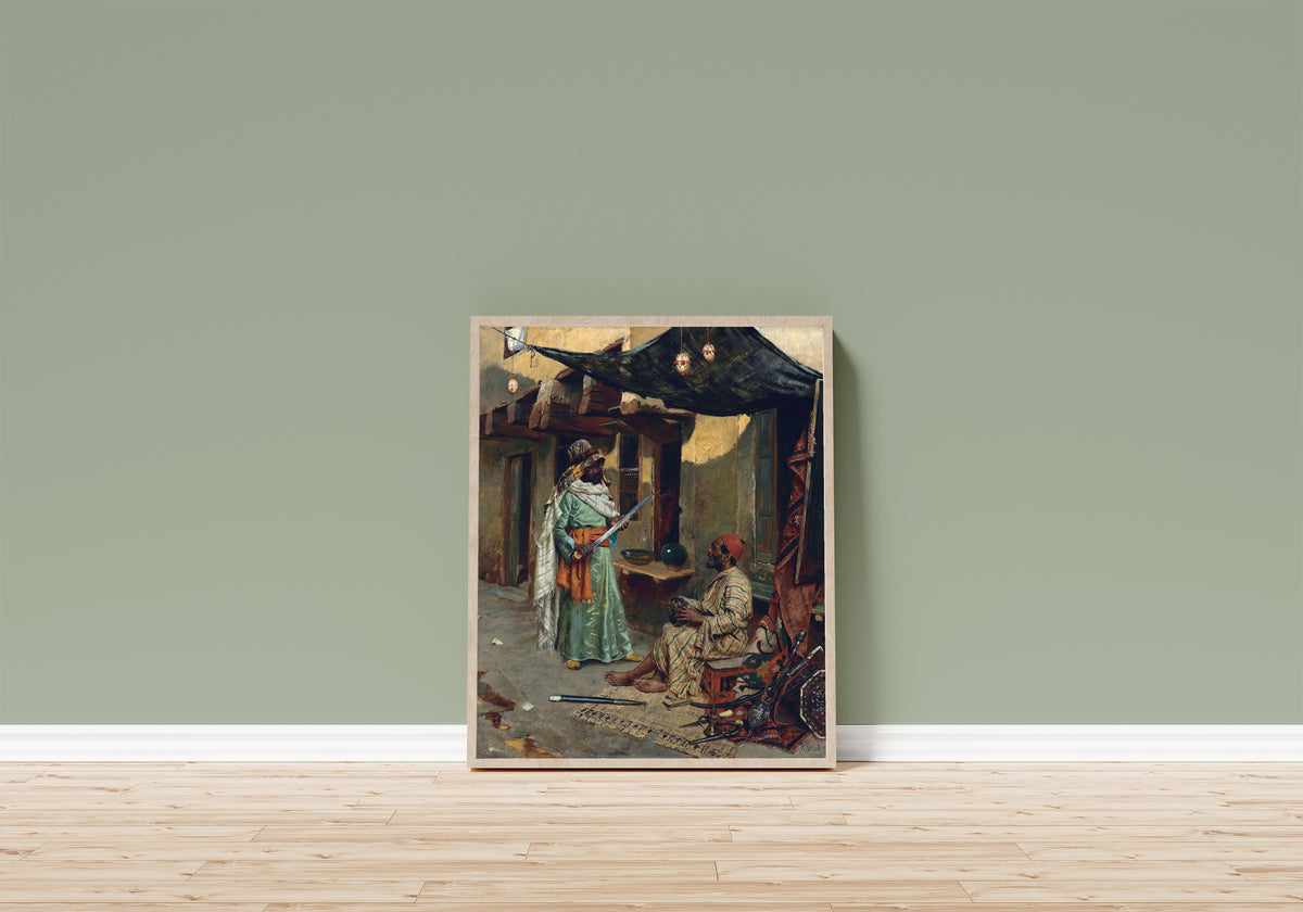 Framed art print of The Arms Merchant by Rudolf Ernst, in a light wood frame leaning on a sage green wall above a wooden floor
