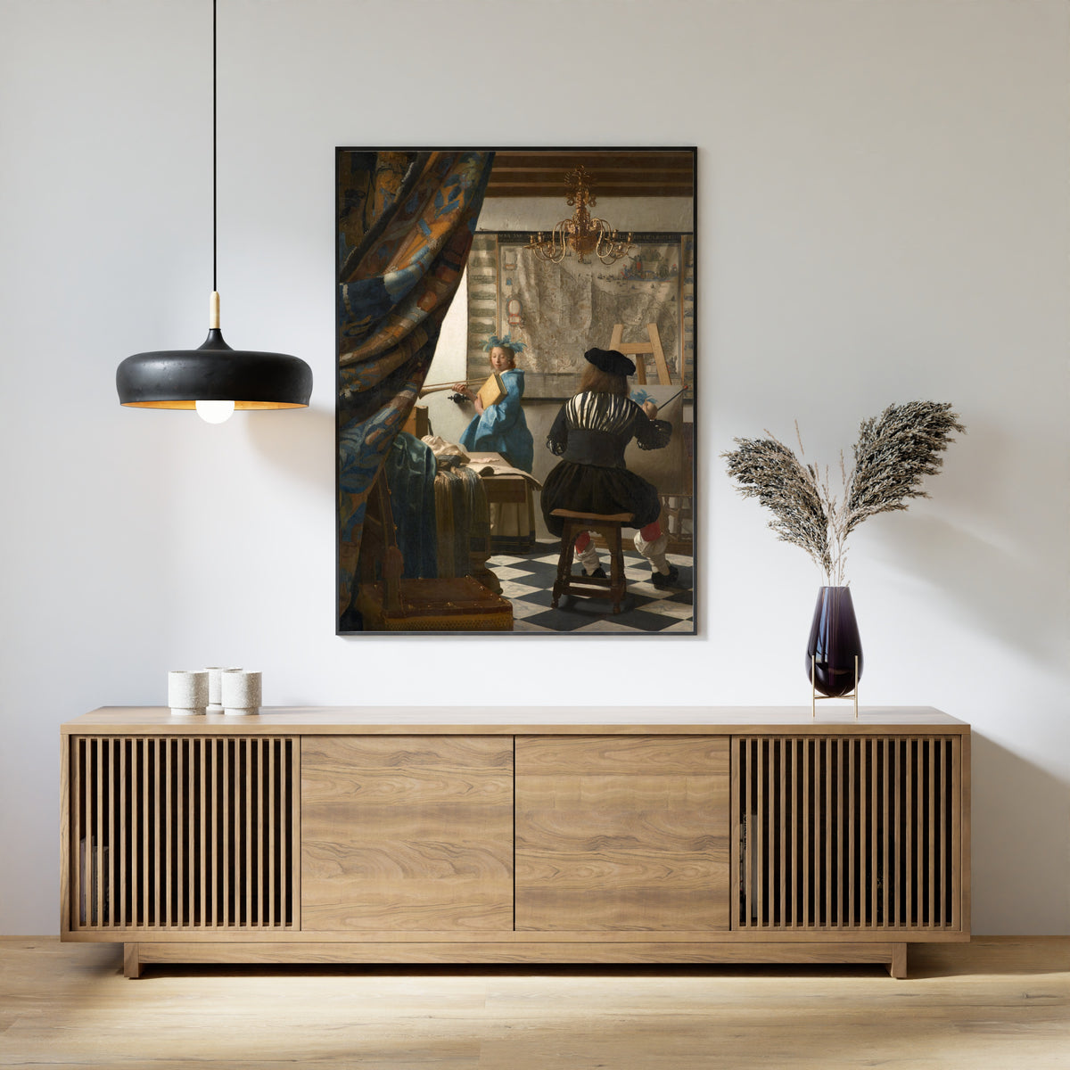 Framed art print of The Art of Painting by Johannes Vermeer, above a slatted wood sideboard