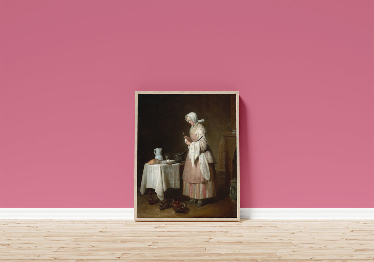 Framed art print of The Attentive Nurse by Jean-Siméon Chardin, in a light wood frame leaning on a pink wall above a wooden floor