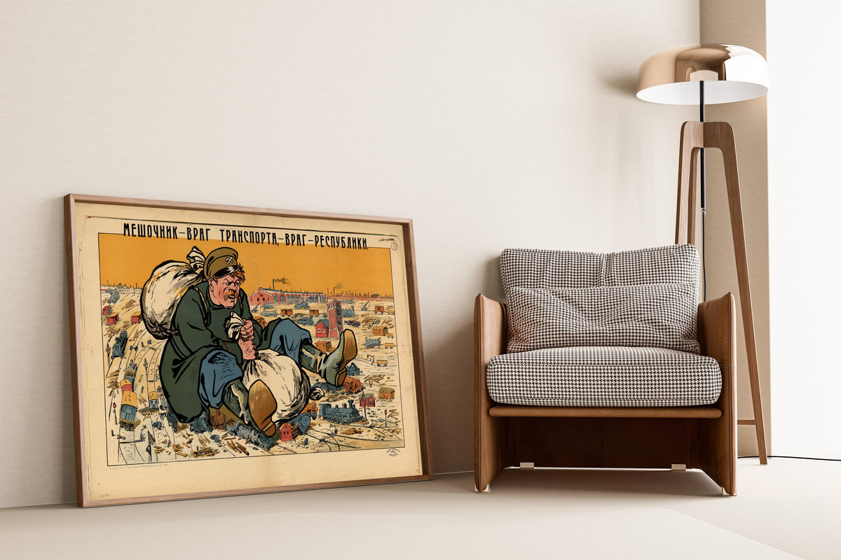 Framed art print of The Bagman Is the Enemy of Transport, the Enemy of the Republic, leaning against a wall beside an armchair and a floor lamp