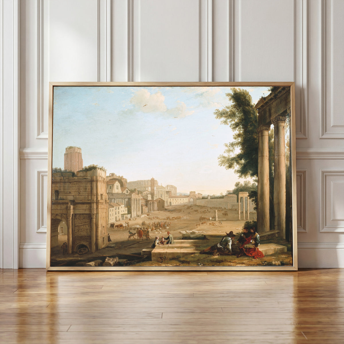 Framed art print of The Campo Vaccino, Rome by Claude Lorrain, in a light wood frame leaning against a panelled white wall