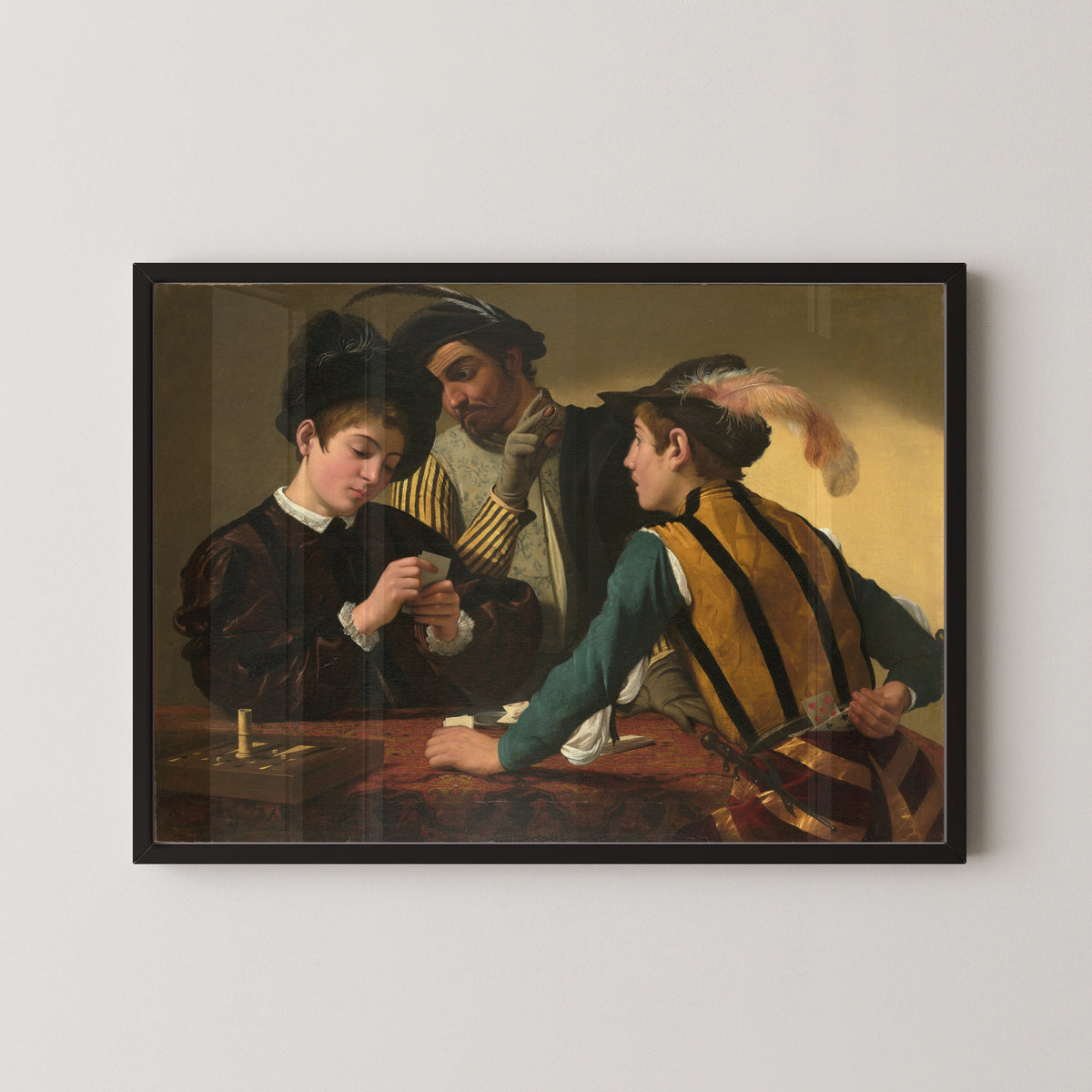 Framed art print of The Cardsharps by Caravaggio, in a black frame on a pale wall