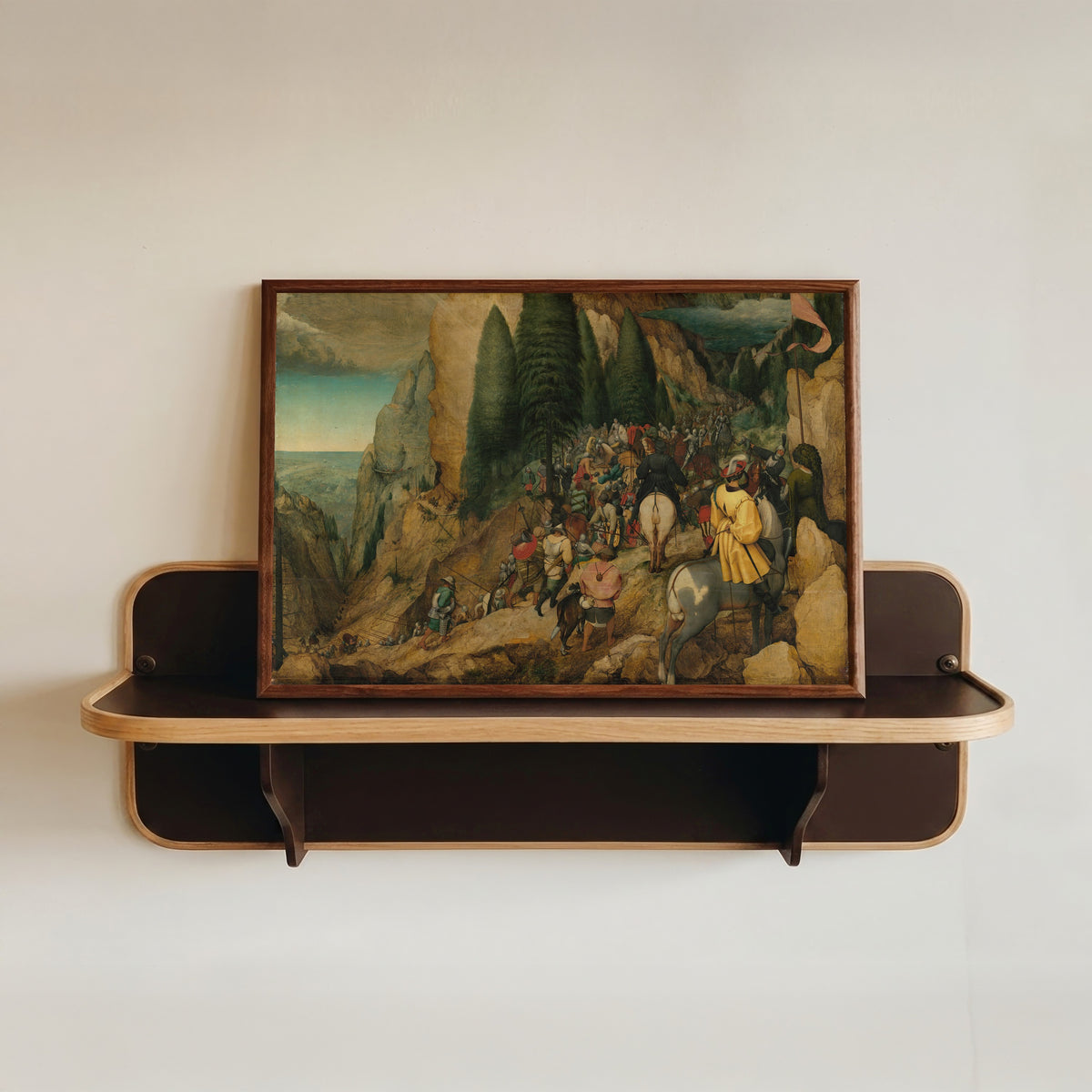 Framed art print of The Conversion of Paul by Pieter Bruegel the Elder, in a dark wood frame resting on a wall shelf
