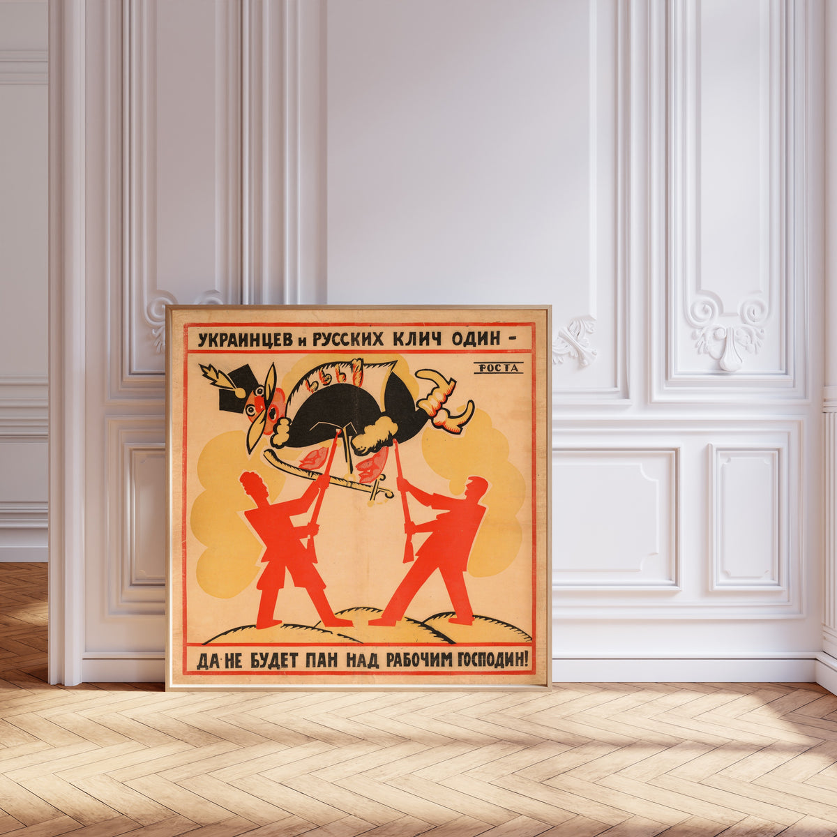 Framed art print of The Cry of Ukrainians and Russians Is One: Let No Lord… by Vladimir Mayakovsky, leaning against pale pink panelling on a herringbone floor