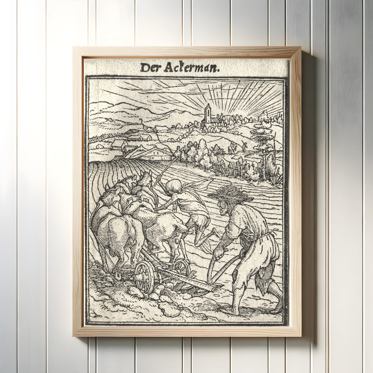 Framed art print of The Dance of Death: Der Ackerman (The Ploughman) by Hans Holbein the Younger, in a light wood frame on a white panelled wall