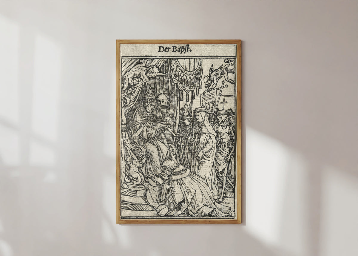 Framed art print of The Dance of Death: Der Bapst (The Pope) by Hans Holbein the Younger, in a light wood frame on a sunlit white wall
